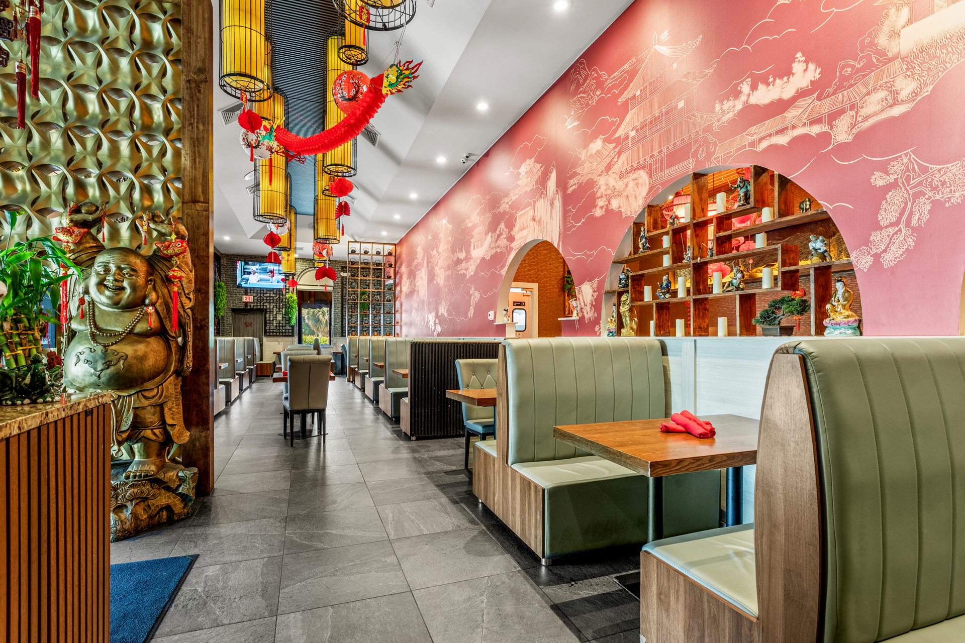 Interior of Peking Duck Restaurant featuring dining booths, a golden Buddha statue, and traditional red dragon decor.