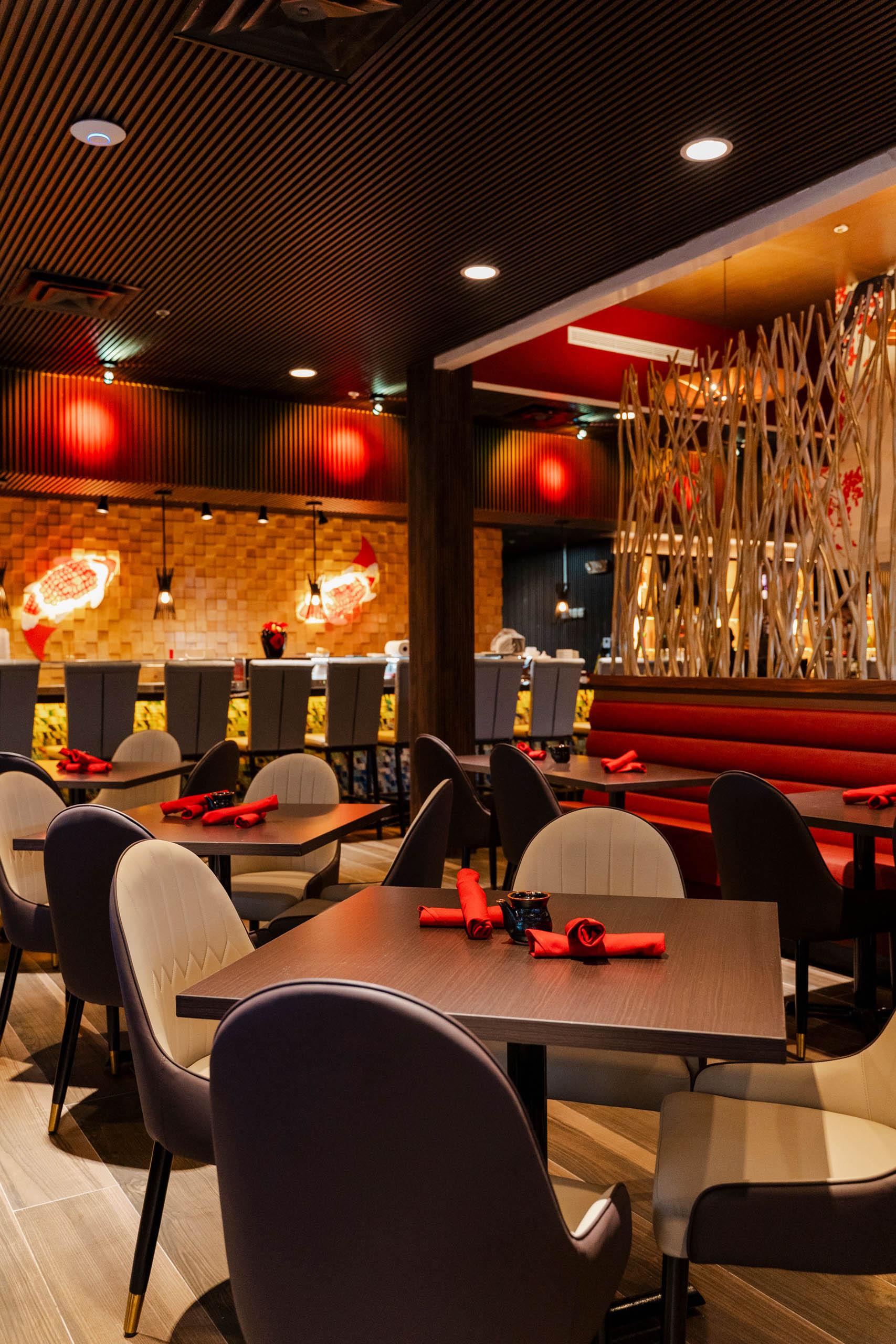 Interior view of Saiko-i Coral Springs featuring a lit sushi bar with modern grey tufted bar stools.