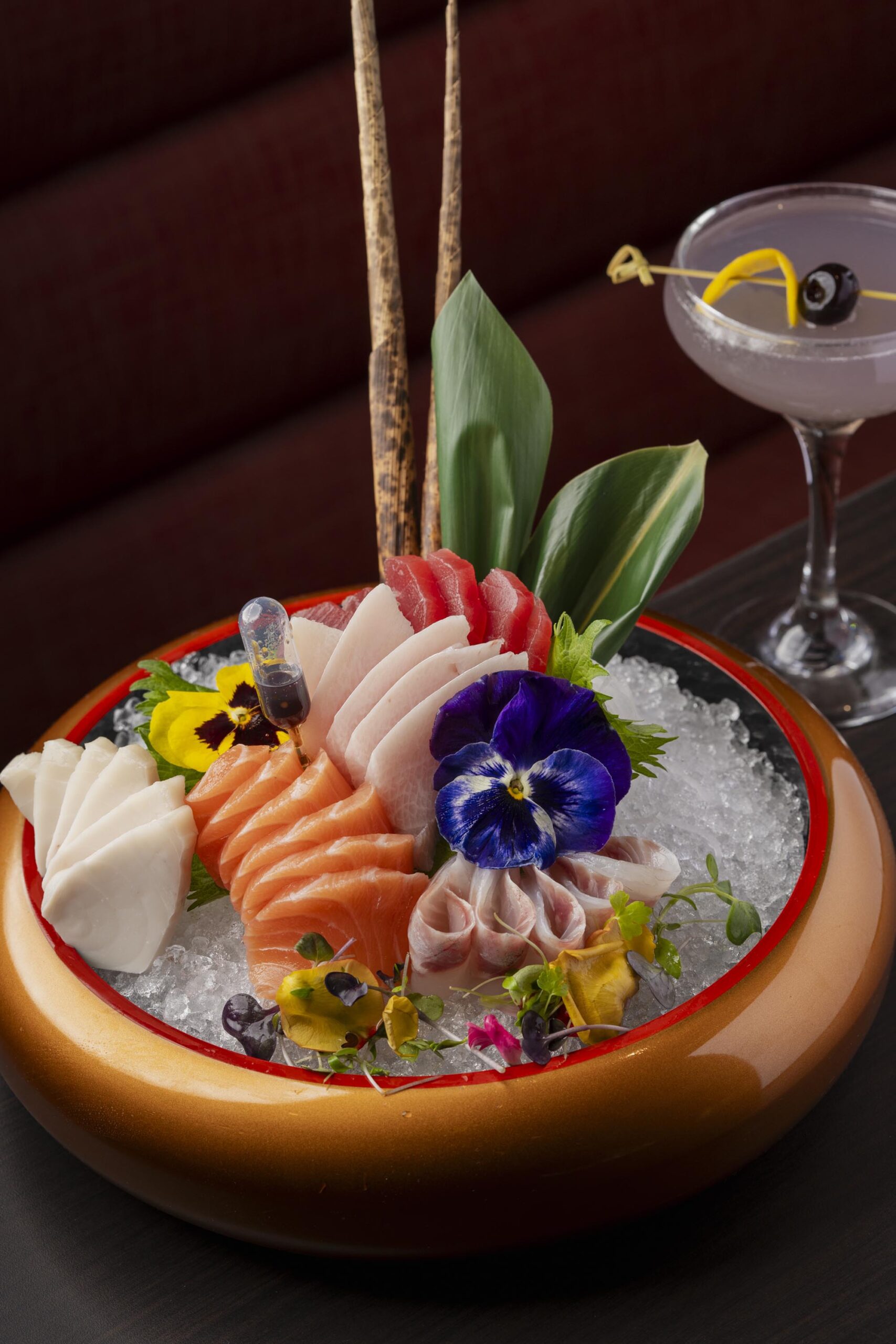 Assorted sashimi platter on ice with tuna, salmon, and white fish, garnished with edible flowers and bamboo stalks. Assorted sashimi platter on ice with tuna, salmon, and white fish, garnished with edible flowers and bamboo stalks.